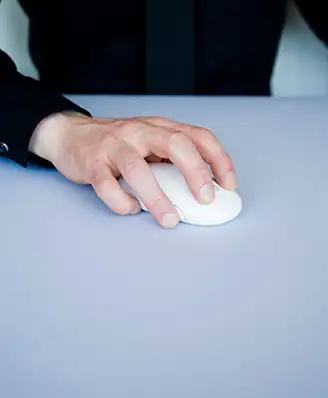 Hand holding a computer mouse on a desk